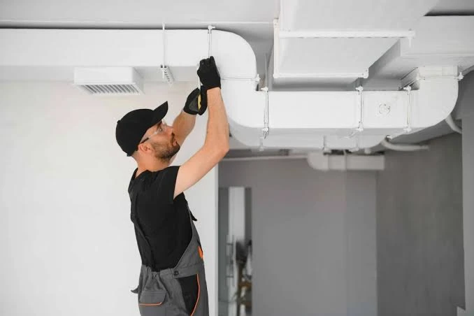 Illustrative HVAC technician checking overhead ventilation ductwork