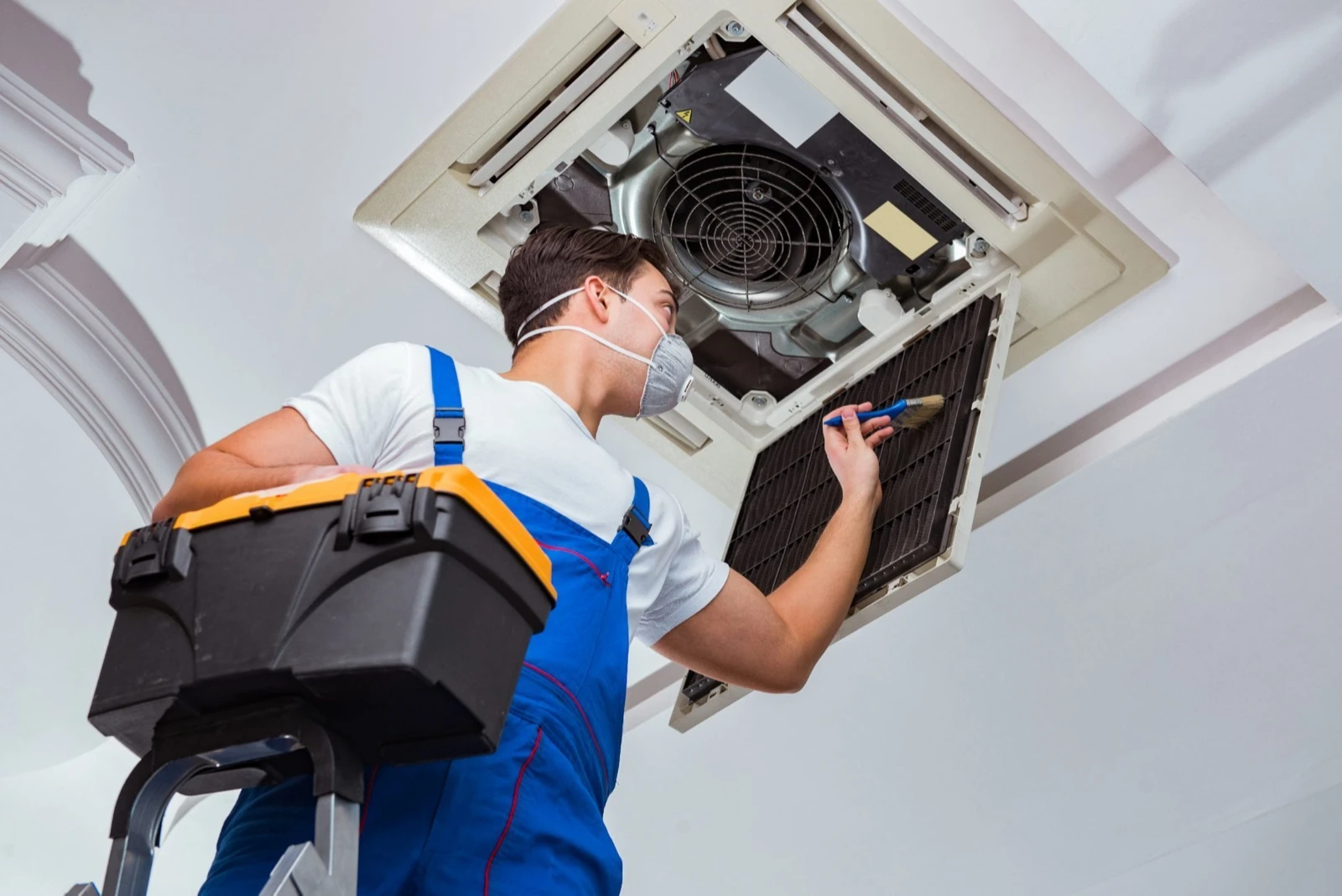 Illustrative technician servicing a ceiling-mounted air conditioning system