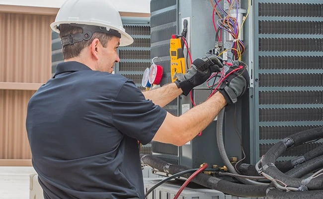 Illustrative HVAC repair technician testing an outdoor unit’s electrical wiring